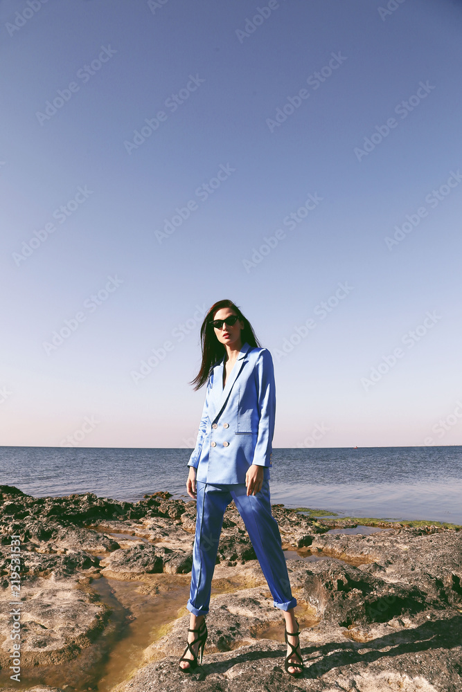 beautiful woman with dark hair in elegant blue suit posing on the summer beach beautiful woman with dark hair in elegant blue suit posing on the summer beach