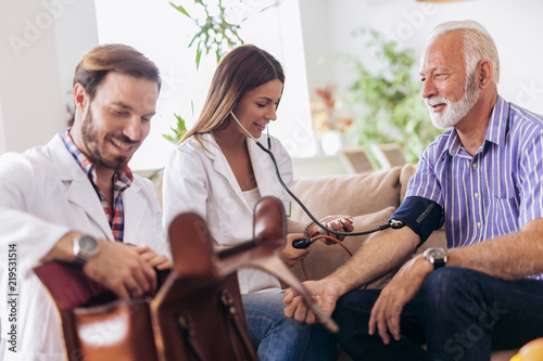 Wallpaper Mural Nurse measuring blood pressure of senior man at home. Smiling to each other. Home care. Torontodigital.ca