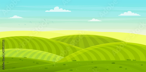 Sunny rural landscape with hills and fields. Summer green hills, meadows and fields with a dawn, blue sky in the clouds.