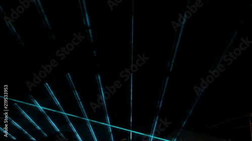 Abstract green and blue laser beams during an evening show on a dark background.
