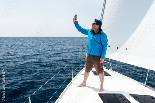 Hipster Man sailing with sails out on a sunny day and making selfie