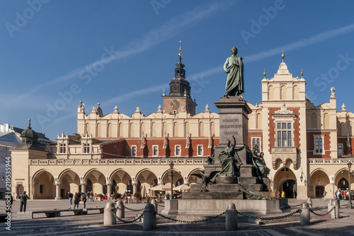 The Adam Mickiewicz statue and the Cloth Hall in the historic center of Krakow, Poland on a beautiful sunny day