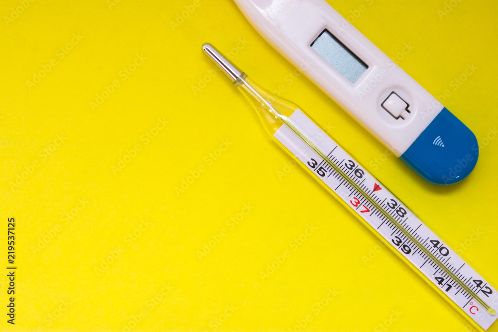 Two medical thermometermercury and electronic, are on uniform yellow