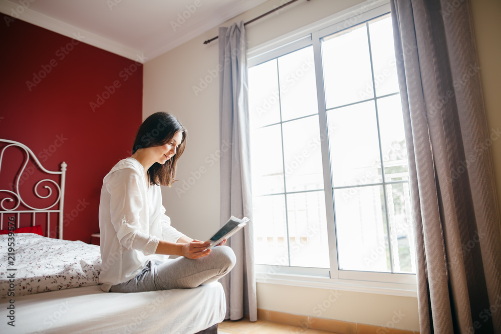 Woman reading book on bed in the morning Woman reading book on bed in the morning