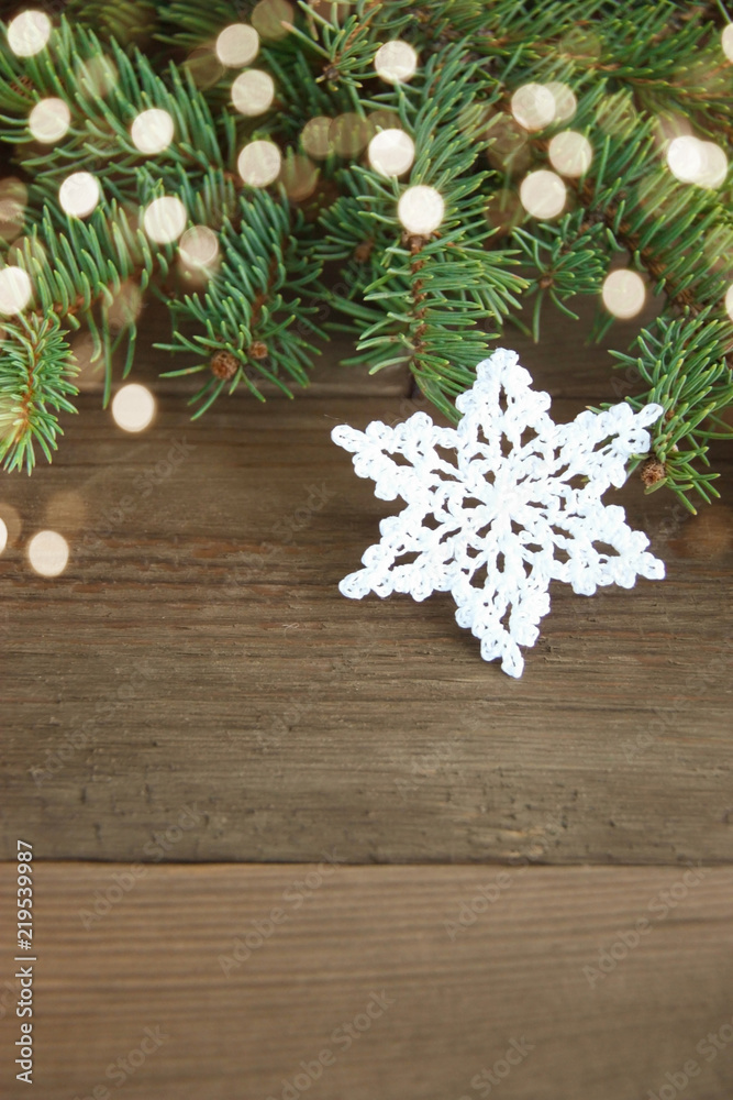 White cotton crocheted snowflakes with yarn ball near green christmas fur tree on the rustic wooden background. Christmas card, postcard concept. Front view. Bright spots of christmas lights. Bokeh. White cotton crocheted snowflakes with yarn ball near green christmas fur tree on the rustic wooden background. Christmas card, postcard concept. Front view. Bright spots of christmas lights. Bokeh.