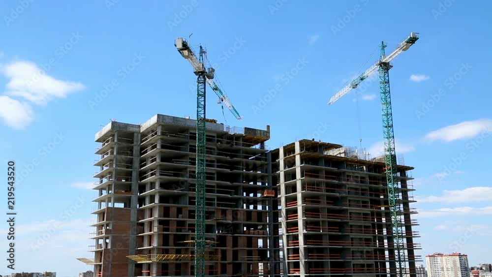 Construction cranes against the blue sky build a multi-storey building Construction cranes against the blue sky build a multi-storey building