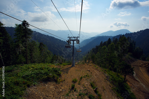 Cable car road in Sochi in Rosa Khutor under blue sky with green forest