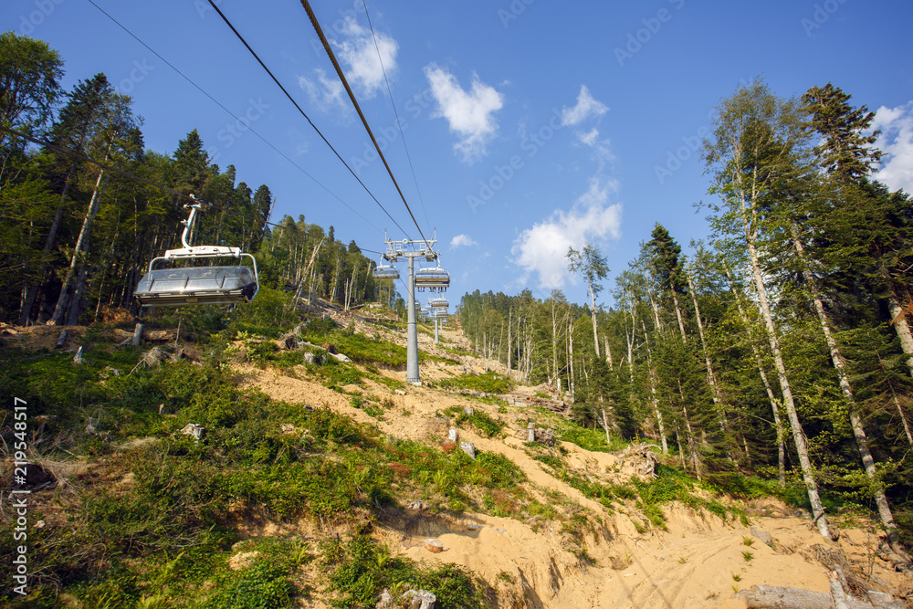 Cable car road in Sochi in Rosa Khutor under blue sky with green forest