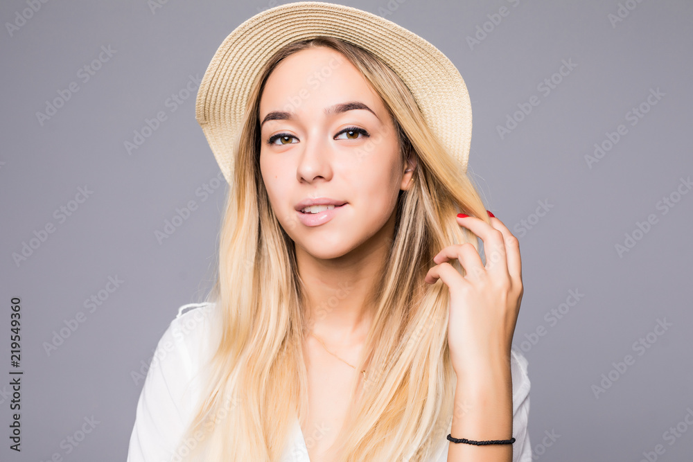 Portrait of young trendy female wearing straw hat, isolated on gray background Portrait of young trendy female wearing straw hat, isolated on gray background