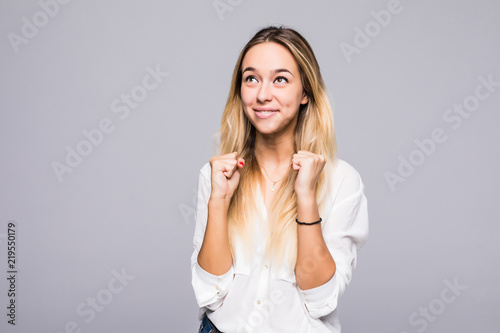 Portrait of a happy young blonde girl celebrating success over gray background