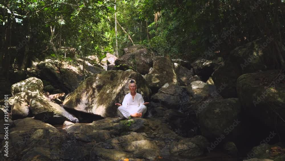 Woman Meditates in lotus pose near nature streams .Practice Meditation in the Nature. Relaxing Woman Meditates in lotus pose near nature streams .Practice Meditation in the Nature. Relaxing