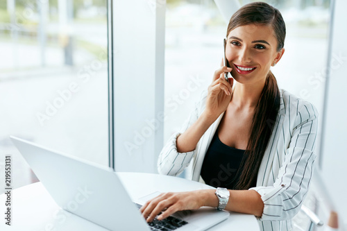 Woman Working On Notebook, Using Phone In Office © puhhha