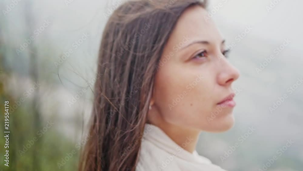 A girl on a high mountain in windy weather. Long-haired beautiful brunette