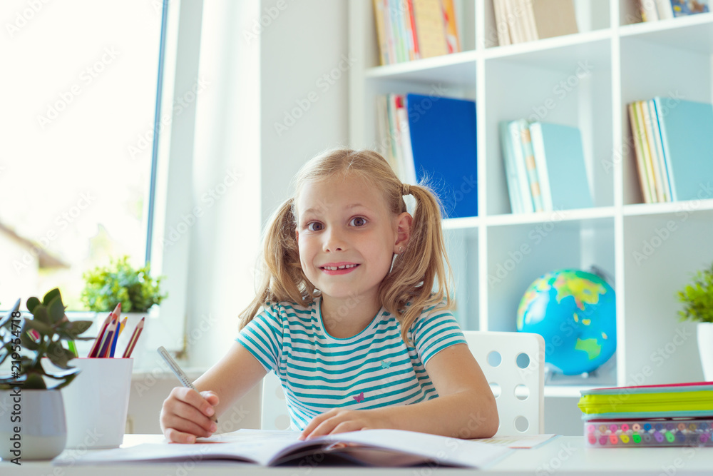 Portrait of schoolgirl at classroom writing at the table