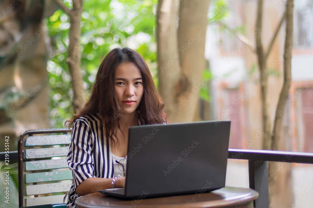 Young freelance woman using laptop to work outside coffee shop. Business person using laptop to communicate. Female student using laptop and study outside cafe in free time. Young freelance woman using laptop to work outside coffee shop. Business person using laptop to communicate. Female student using laptop and study outside cafe in free time.