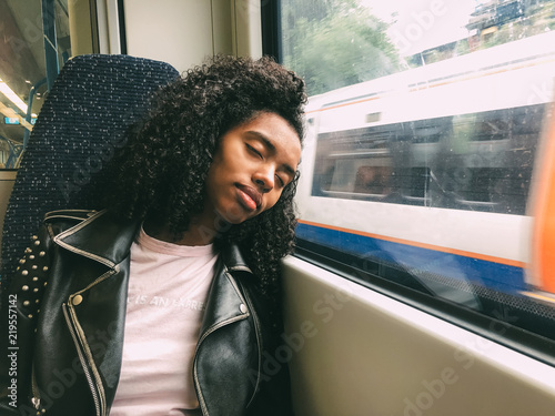 Tired black woman sleeping on the train