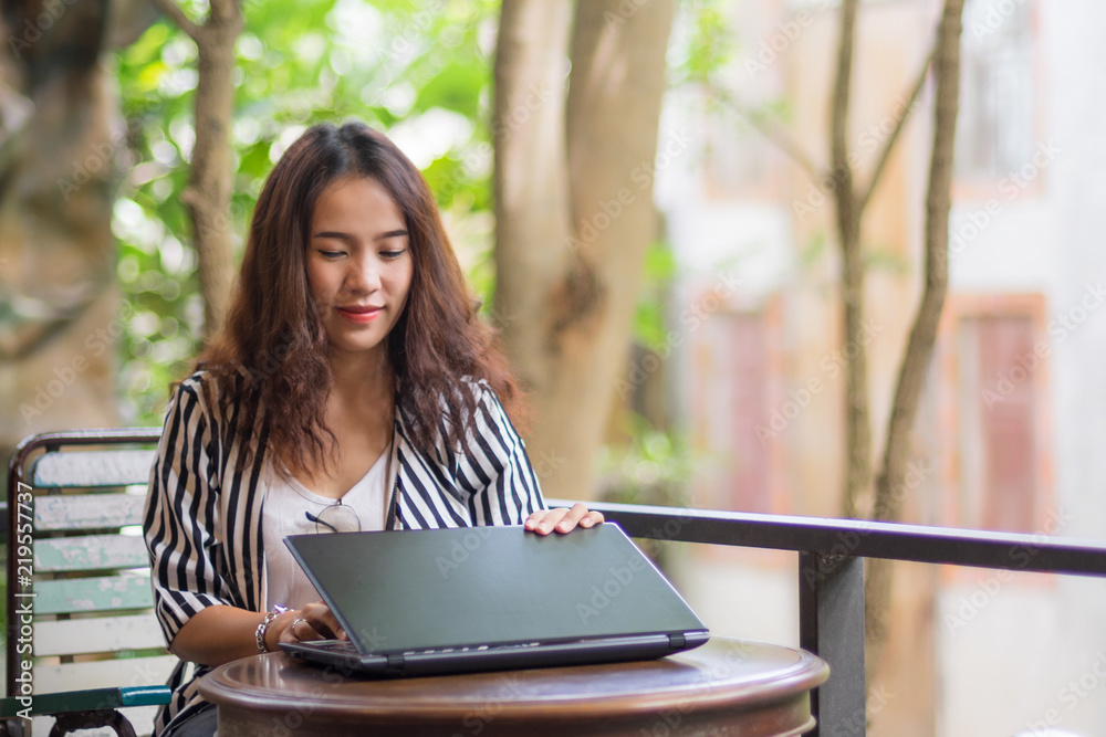Young freelance woman using laptop to work outside coffee shop. Business person using laptop to communicate. Female student using laptop and study outside cafe in free time.