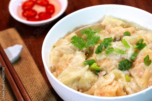 Shrimp wonton in hot soup in white bowl on wooden table Asia food