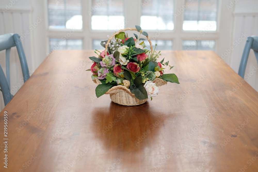 Fototapeta premium artificial rose bouquet on wood table in cozy dining room interior