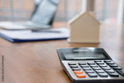 calculator & house model at real estate office. mortgage & property concept