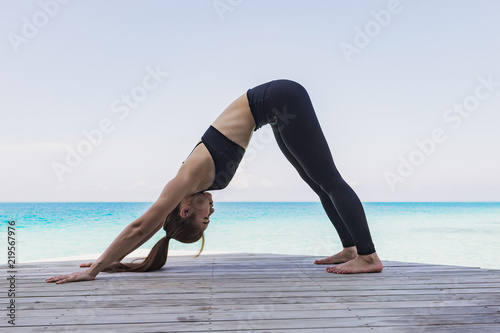 Asian woman practicing yoga Downward Facing Dog or Adho Mukha Svanasana Pose stretching exercises muscle for warm up on the beach in Maldives with seaside,Feeling so comfortable and relax in holiday