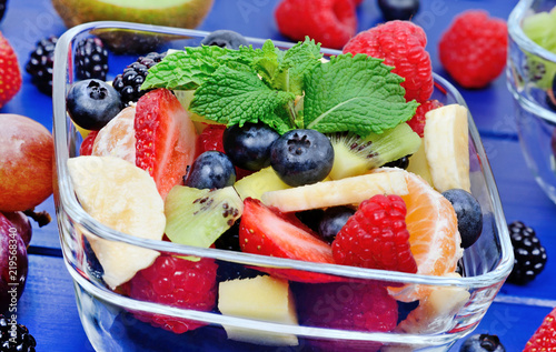 Colorful fruit salad in a transparent bowl on table