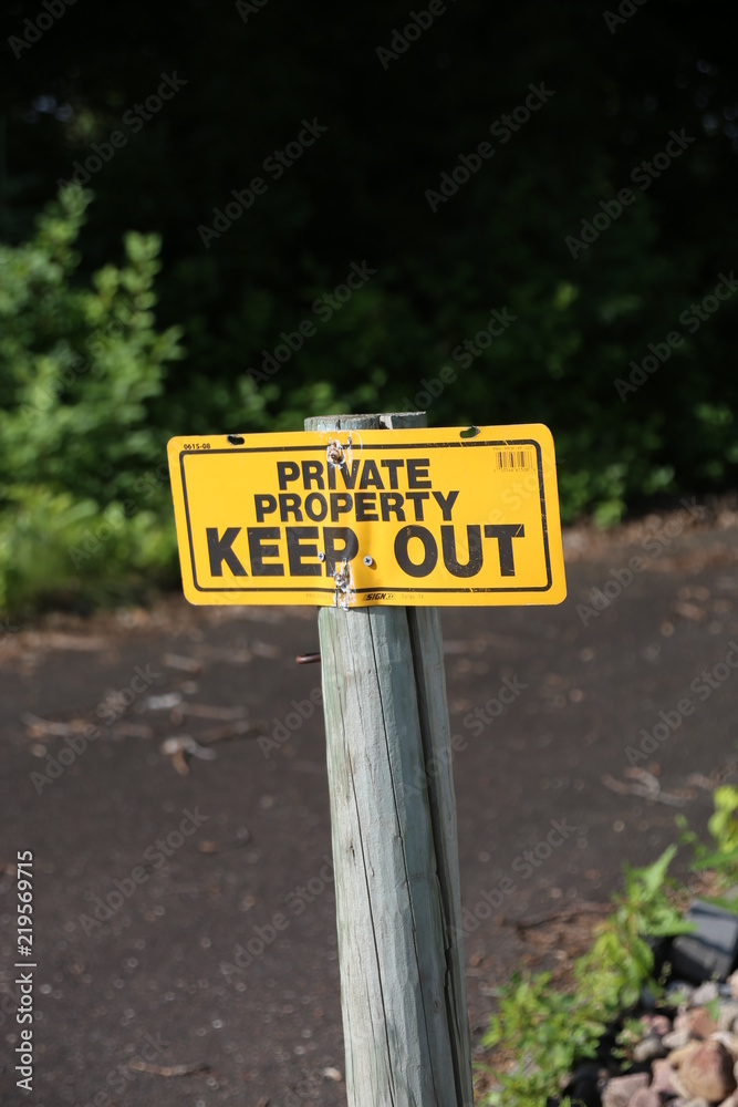 A bright yellow and black sign that states Private Property Keep Out