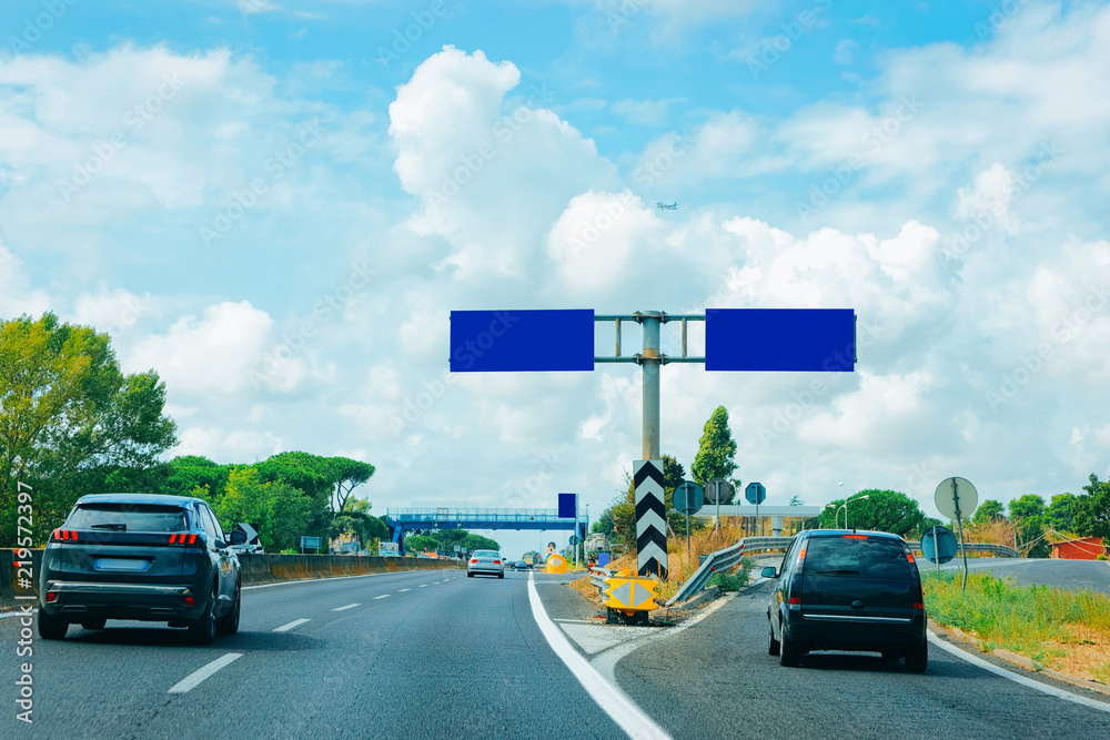 Cars and empty blue traffic signs in road in Italy
