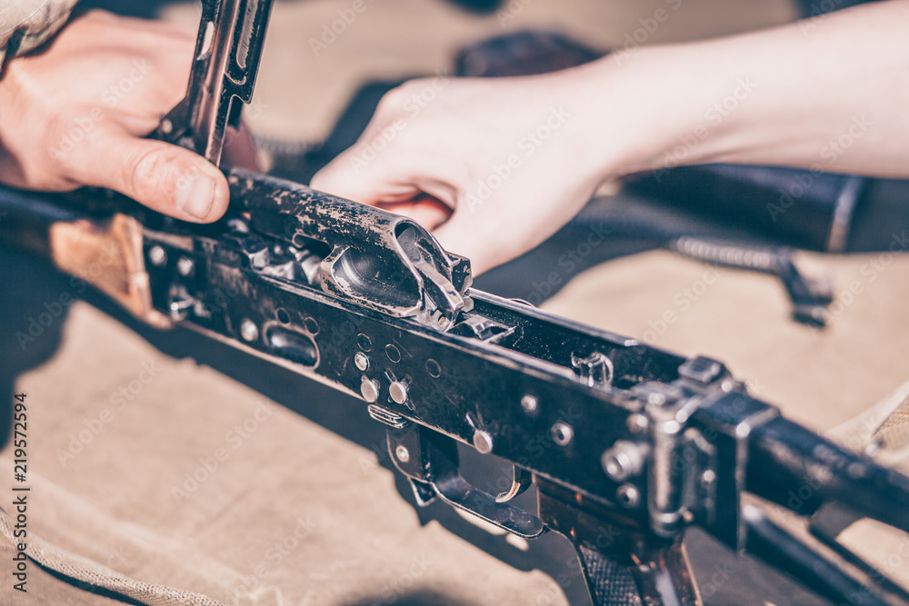The boy performs disassembly, cleaning and assembly of AK-47, an ...