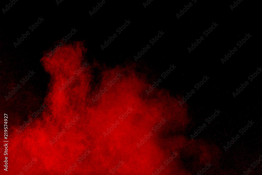 abstract red dust splattered on black background. Red powder explosion.Freeze motion of red particles splashing.