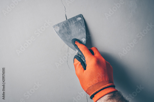 Worker repairs a crack in the wall from shrinkage of the building or poor-quality work photo