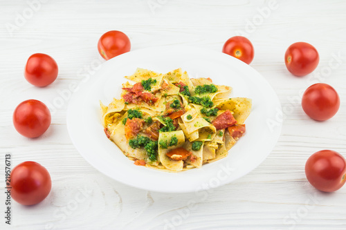 Italian pasta with tomatoes and pesto sauce, on a wooden background