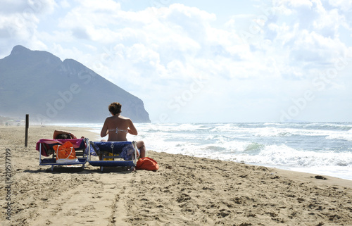 Relaxed women on the Sabaudia desert beach for the summer holidays. The Circeo mountains on the background. Sabaudia, Lazio, Italy