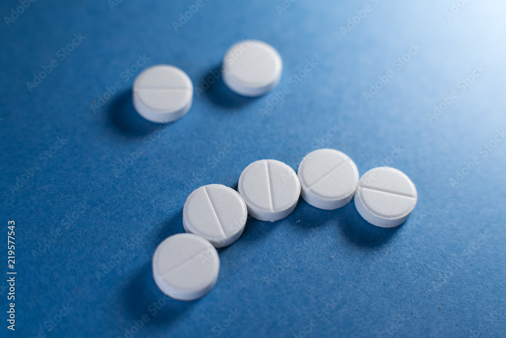 Sad smile made from white pills on blue background Sad smile made from white pills on blue background