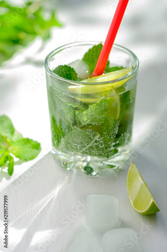 Cold refreshing summer Mojito lemonade in a glass on a white background. Lime, mint, ice.