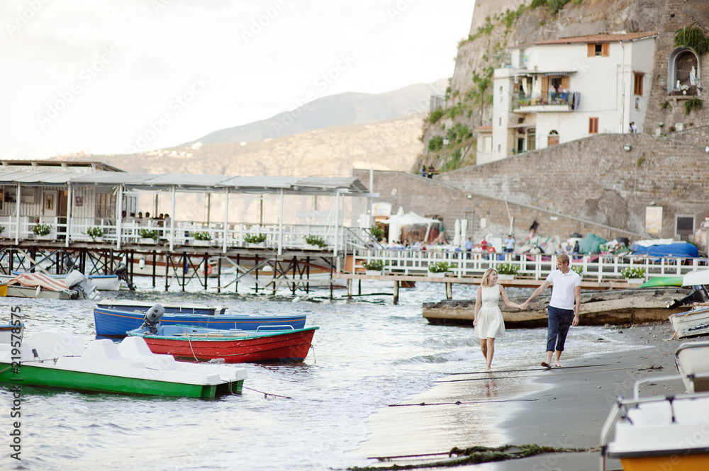 A young couple walks along the beach, in the port of Sorrento.