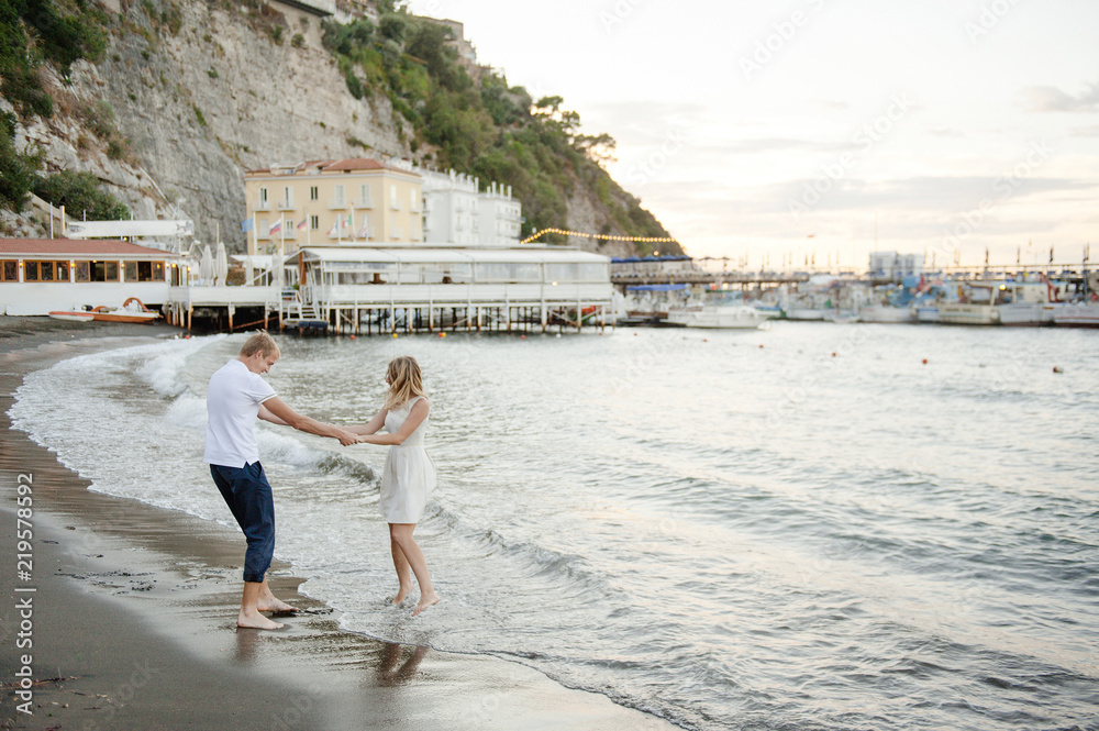 A young couple walks along the beach, in the port of Sorrento. A young couple walks along the beach, in the port of Sorrento.