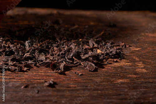 Dried black tea in wooden bowl isolated on white background with clipping path