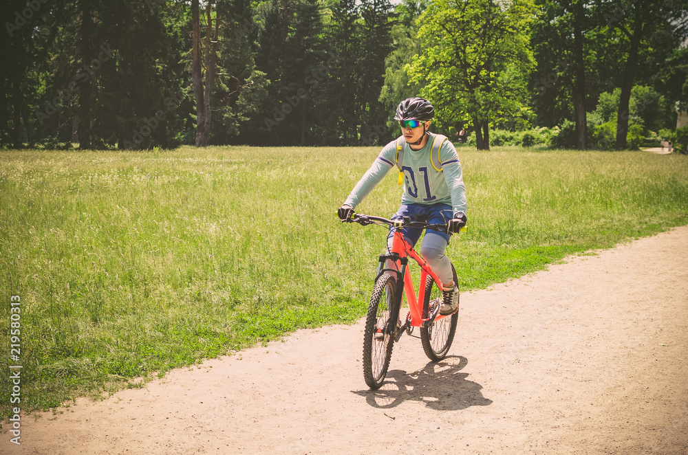 Cyclist in helmet on orange bike riding in park