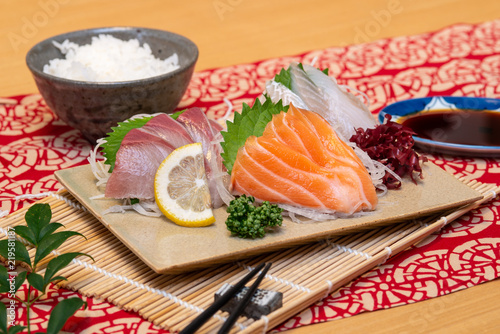sashimi set on a plate with rice and soy sauce and chopsticks