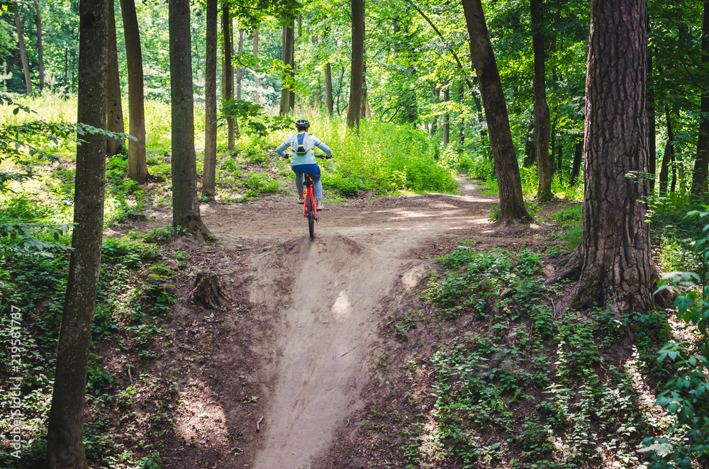 A cyclist in a helmet descends from the mountain on an orange bicycle