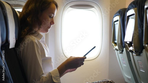 Business woman in airliner texting in smartphone