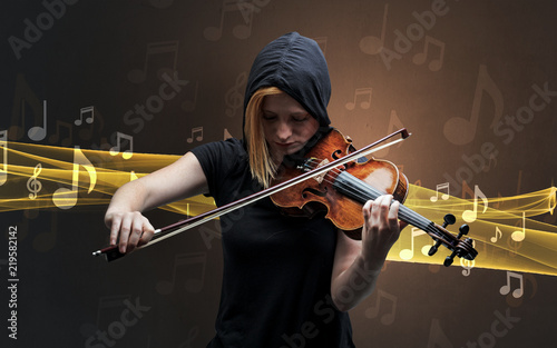 Young male musician playing on his violin with musical notes around photo