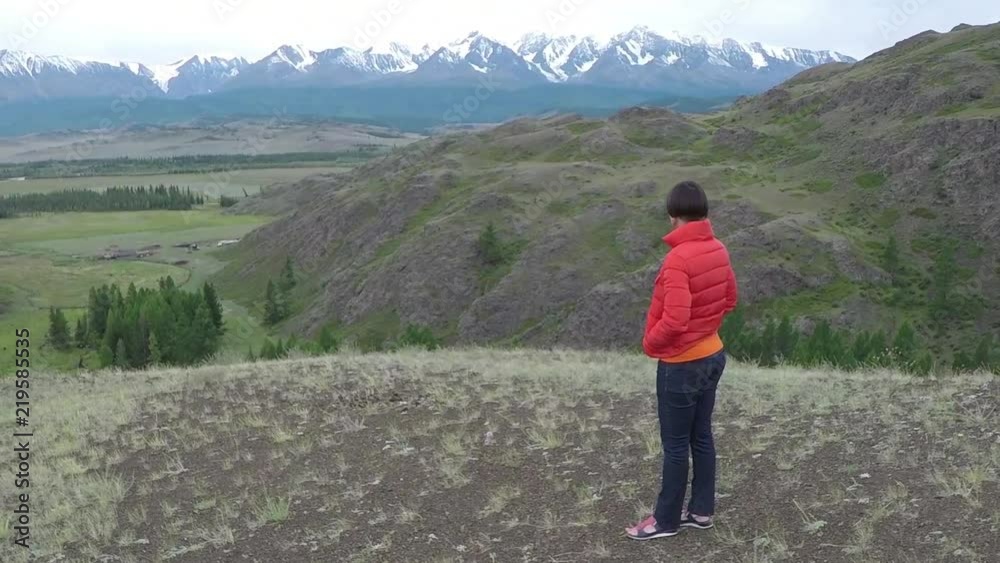 Female hiker proudly standing on mountain top on a cold, cloudy day. Woman standing on top of the mountain. Aerial close up. Female hiker proudly standing on mountain top on a cold, cloudy day. Woman standing on top of the mountain. Aerial close up.