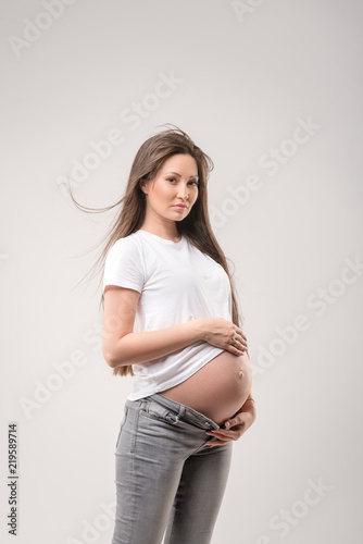 pregnant woman with long hair caressing her belly over white background