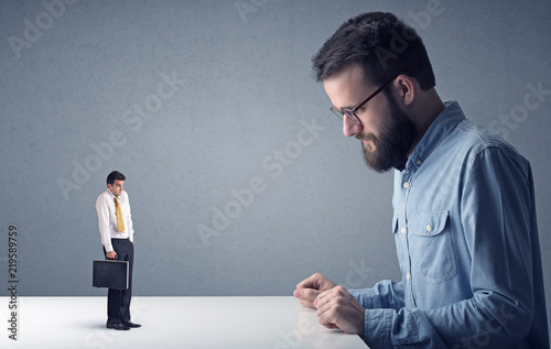 Young professional businessman being angry with an other miniature businessman 
