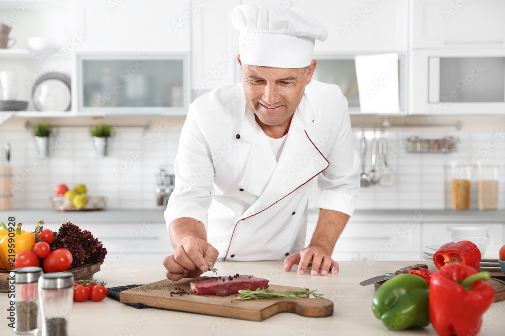 Professional chef cooking meat on table in kitchen Professional chef cooking meat on table in kitchen