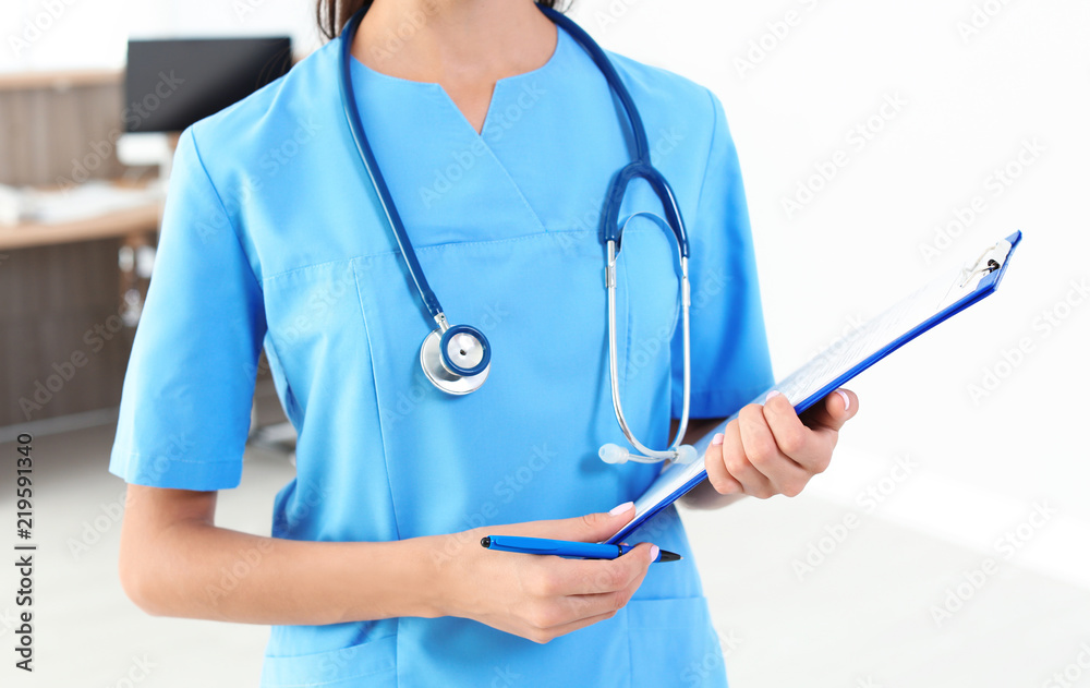 Female medical assistant with clipboard in clinic, closeup. Health care service Female medical assistant with clipboard in clinic, closeup. Health care service