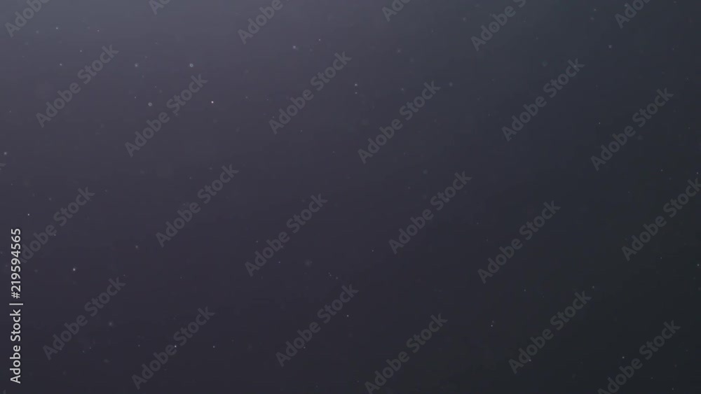 Slow motion backlit dust particles floating in the air on a black background with lens flare