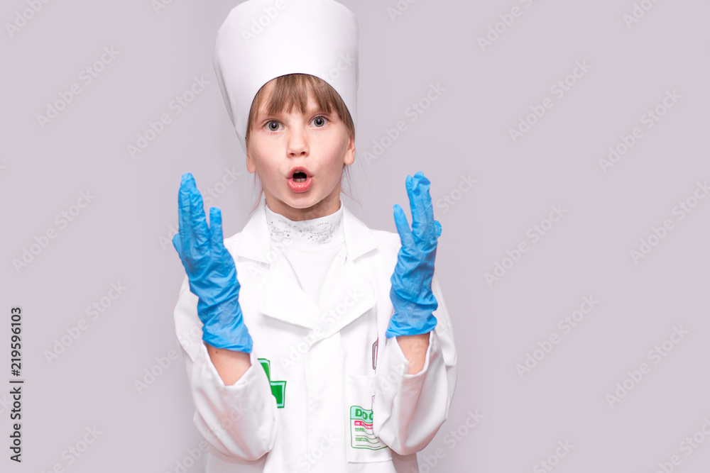 Smiling little girl in medical uniform and blue gloves looking at camera isolated on white Smiling little girl in medical uniform and blue gloves looking at camera isolated on white